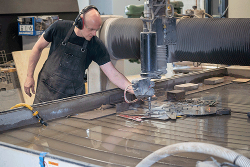 Tom is shown cutting a desgn with the CNC waterjet