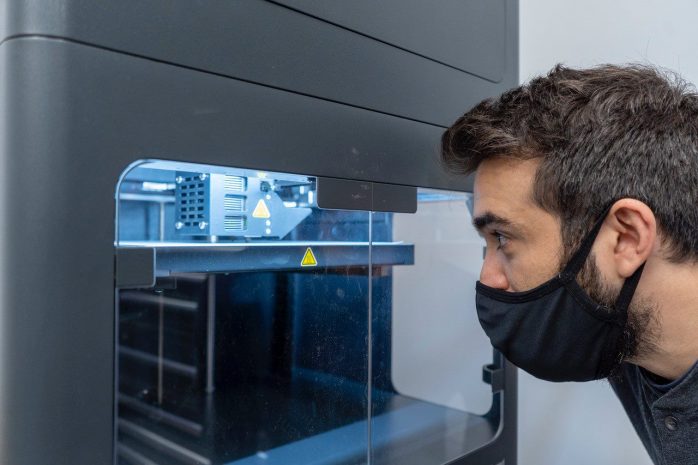 A man looking inside a 3D printing machine