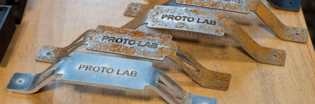 Press formed metal pieces that read "Proto Lab"