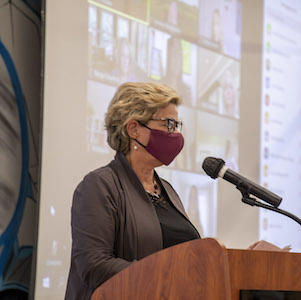 Masked speaker standing at podium