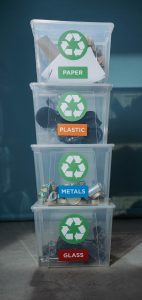 A vertical stack of four clear bins marked paper, plastic, metals, glass. 