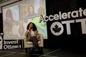 An event speaker sits in a chair on stage at Invest Ottawa's Accelerate Ott event, in a moment of contemplation. 