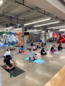 A group exercising on yoga mats in the Foundry at Bayview Yards, appearing to collectively execute yoga positions. 