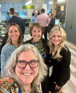 A group of people smiles for a selfie picture at an event together. 