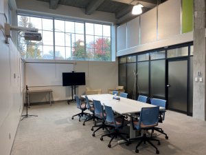 A table is arranged in a meeting room with high ceilings and large windows 