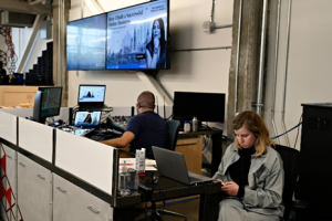 Two people work to manage the technical display at an in-person event.