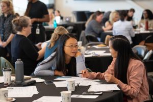 Two people take the opportunity to collaborate at a roundtable workshop event. 