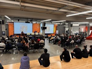 A group is seated, taking in a presentation. 